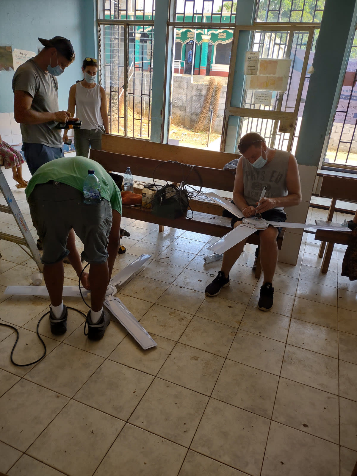 Volunteers build wooden benches in a tiled room