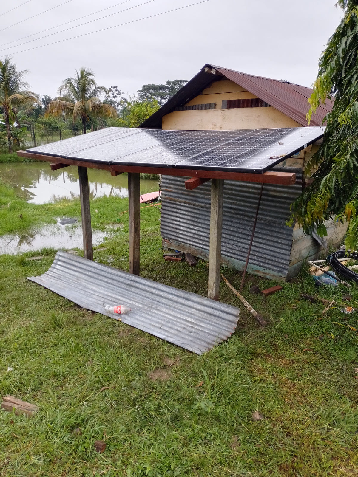A small open shelter with a metal roof beside a flooded field