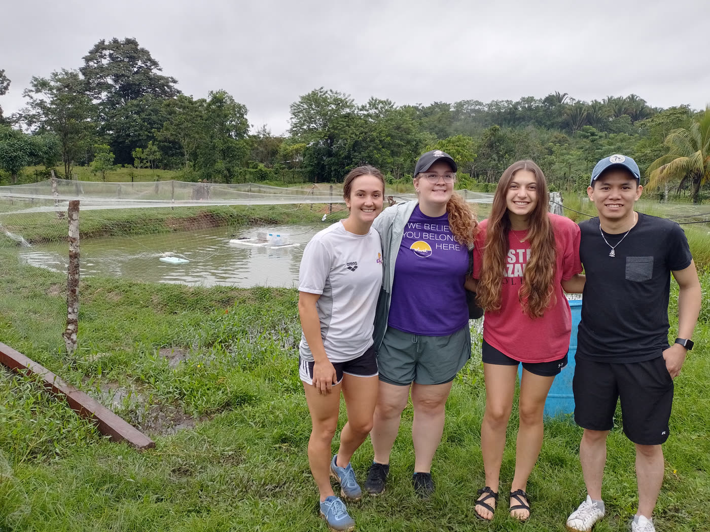Four visitors stand together beside fish ponds