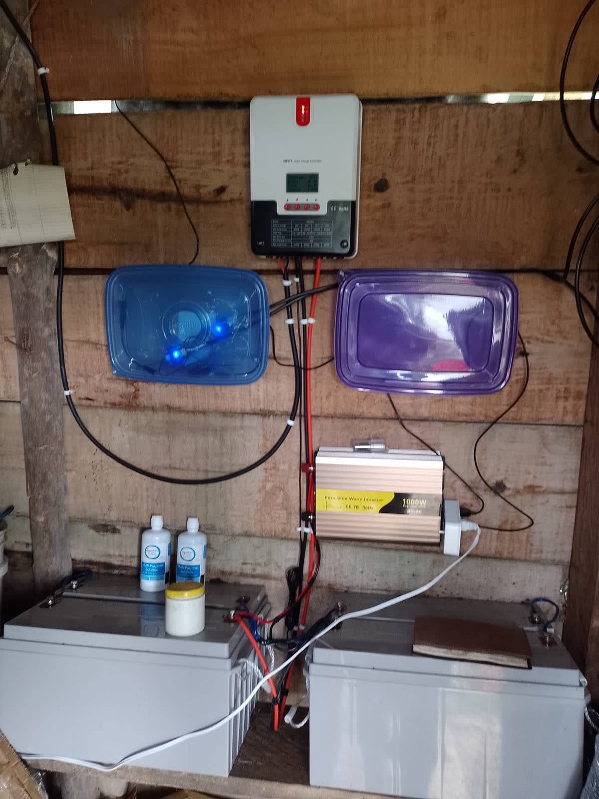 Solar charge controller, inverter, and batteries mounted on a wooden wall
