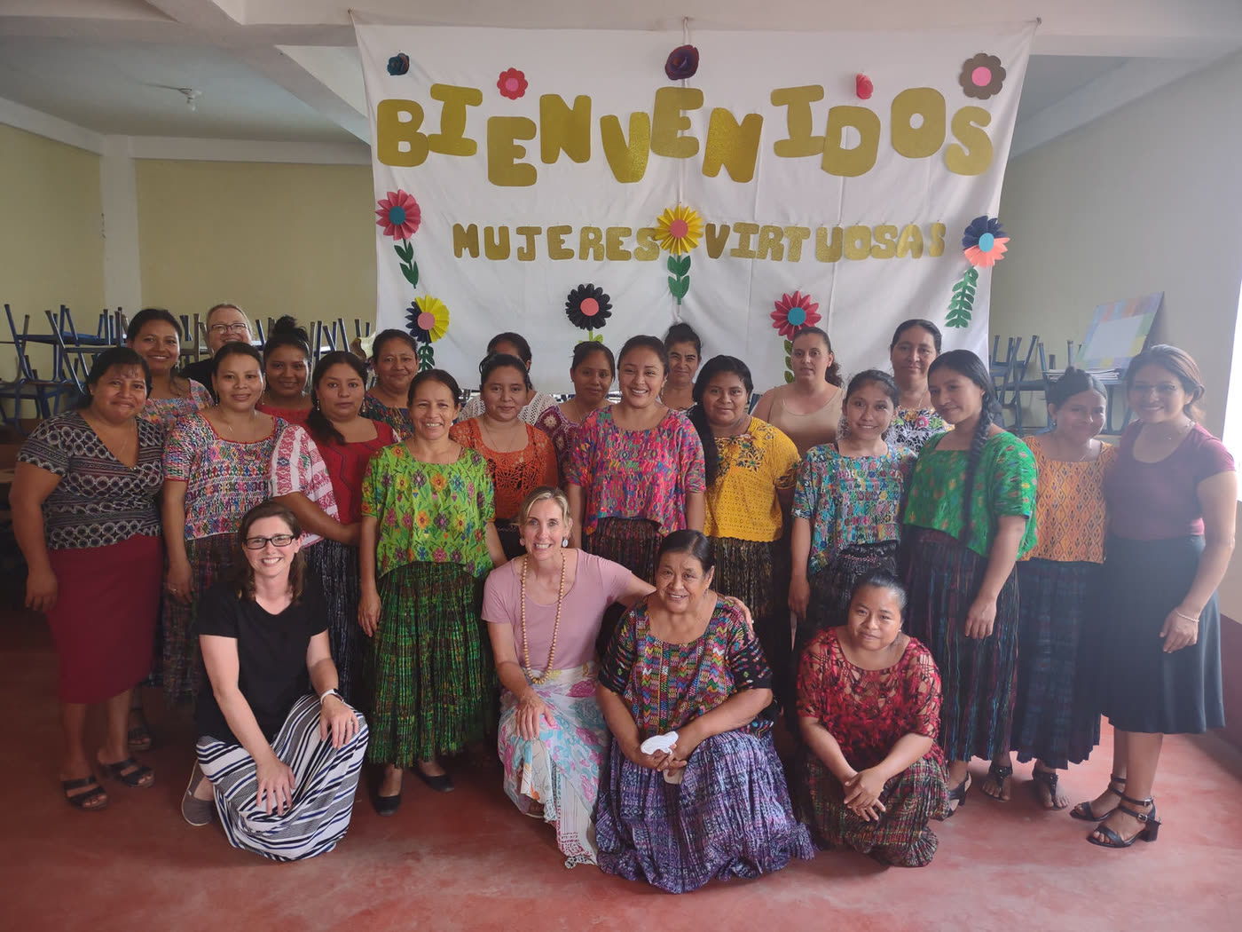 A group of women in front of a banner reading Bienvenidos Mujeres Virtuosas