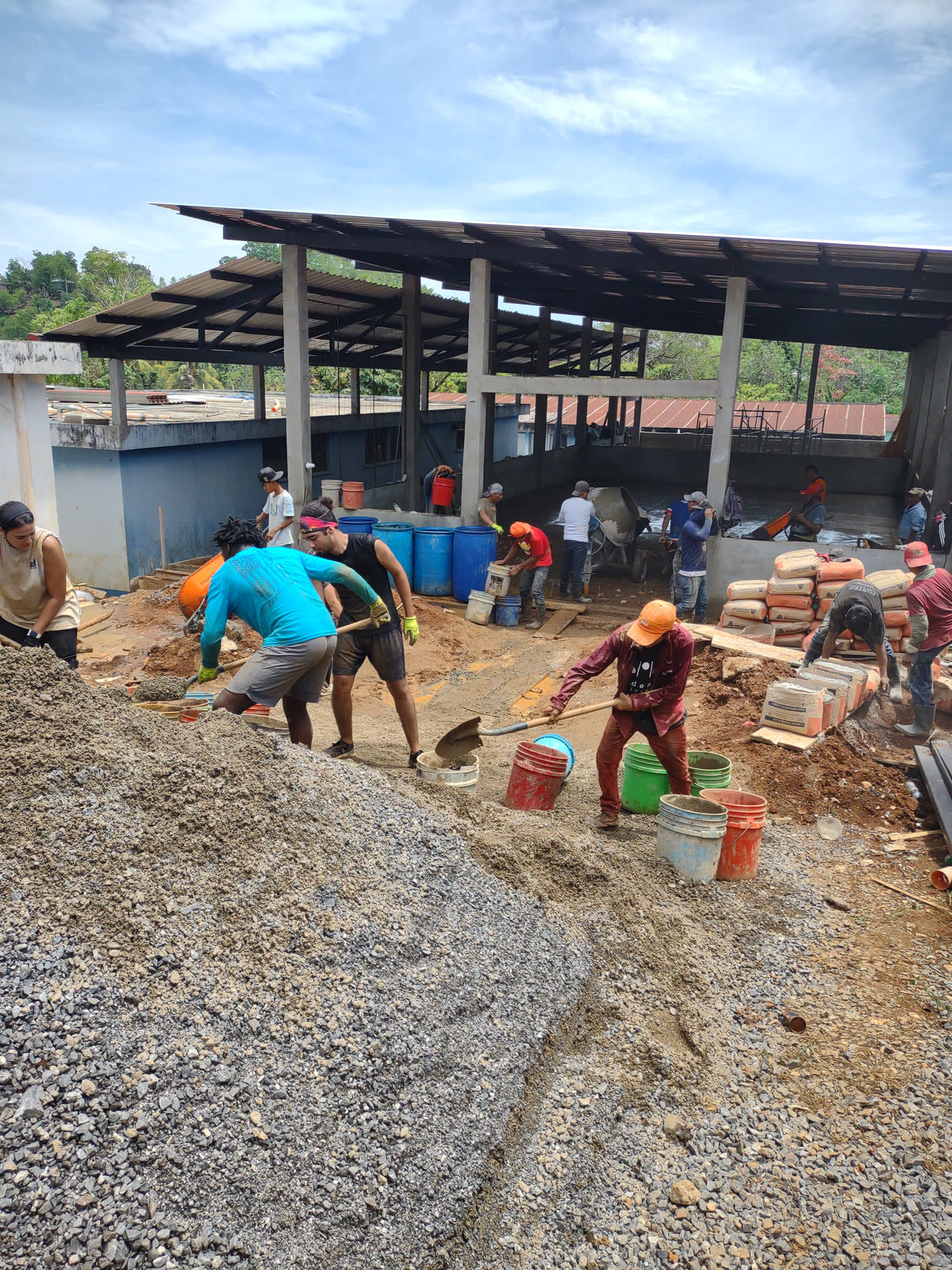 Construction crew mixing concrete for a new clinic building