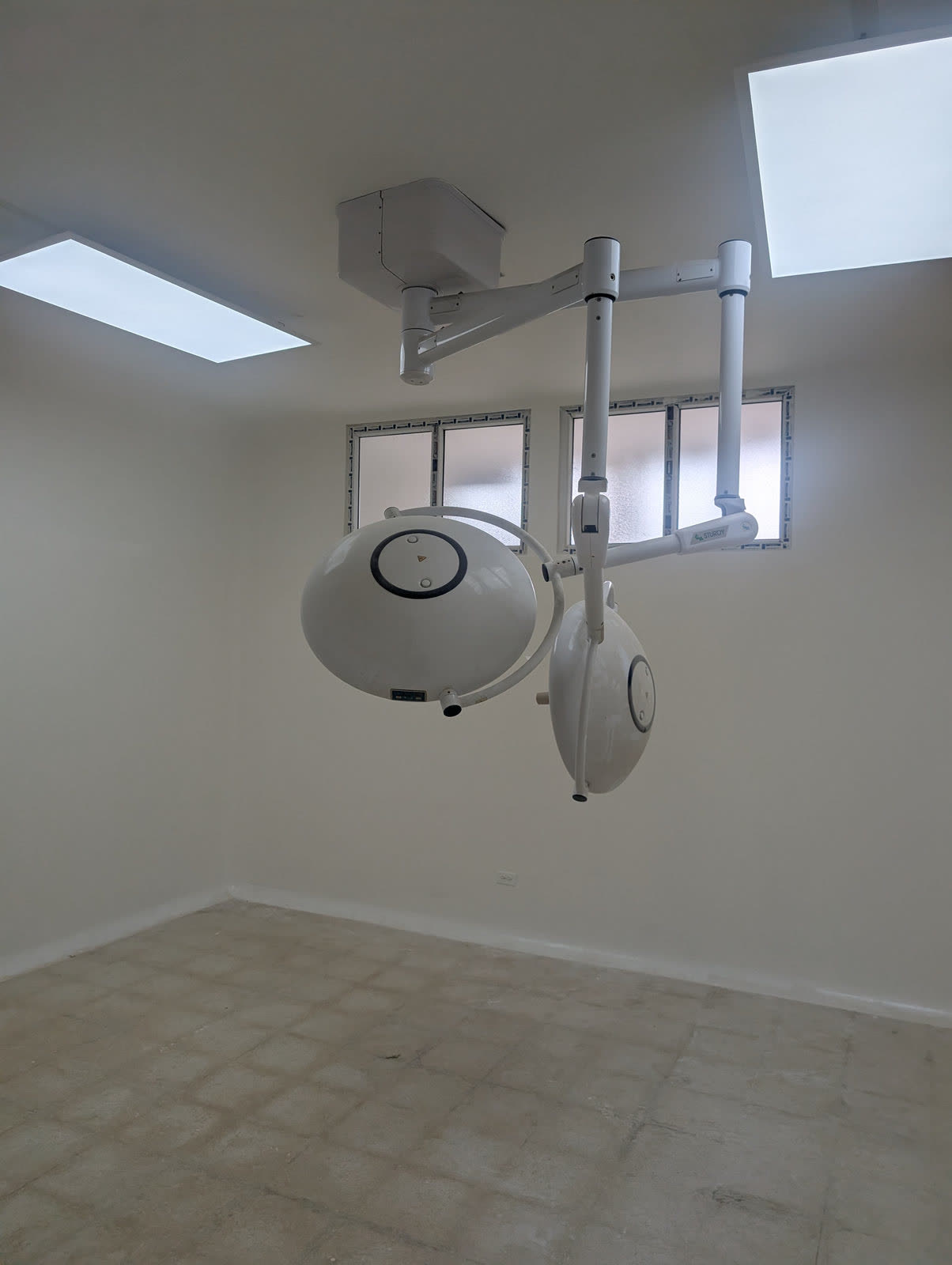 A finished clinic room with a ceiling-mounted surgical light