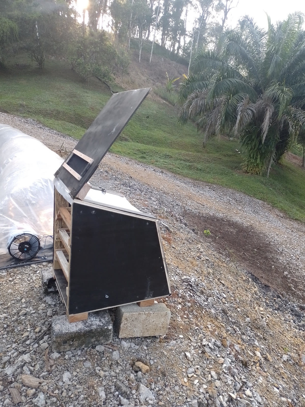 Prototype solar dryer cabinet on a gravel slope