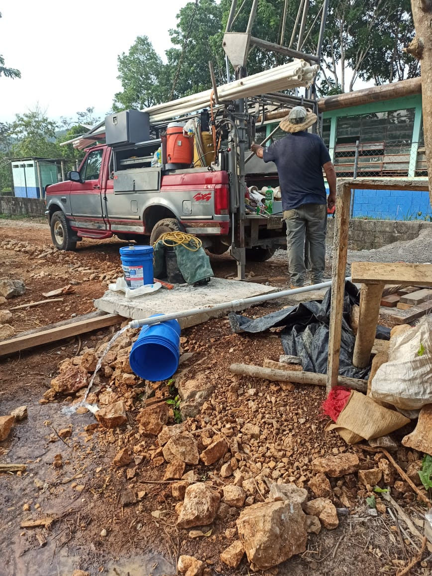 Well-drilling crew and pickup truck at a village drilling site